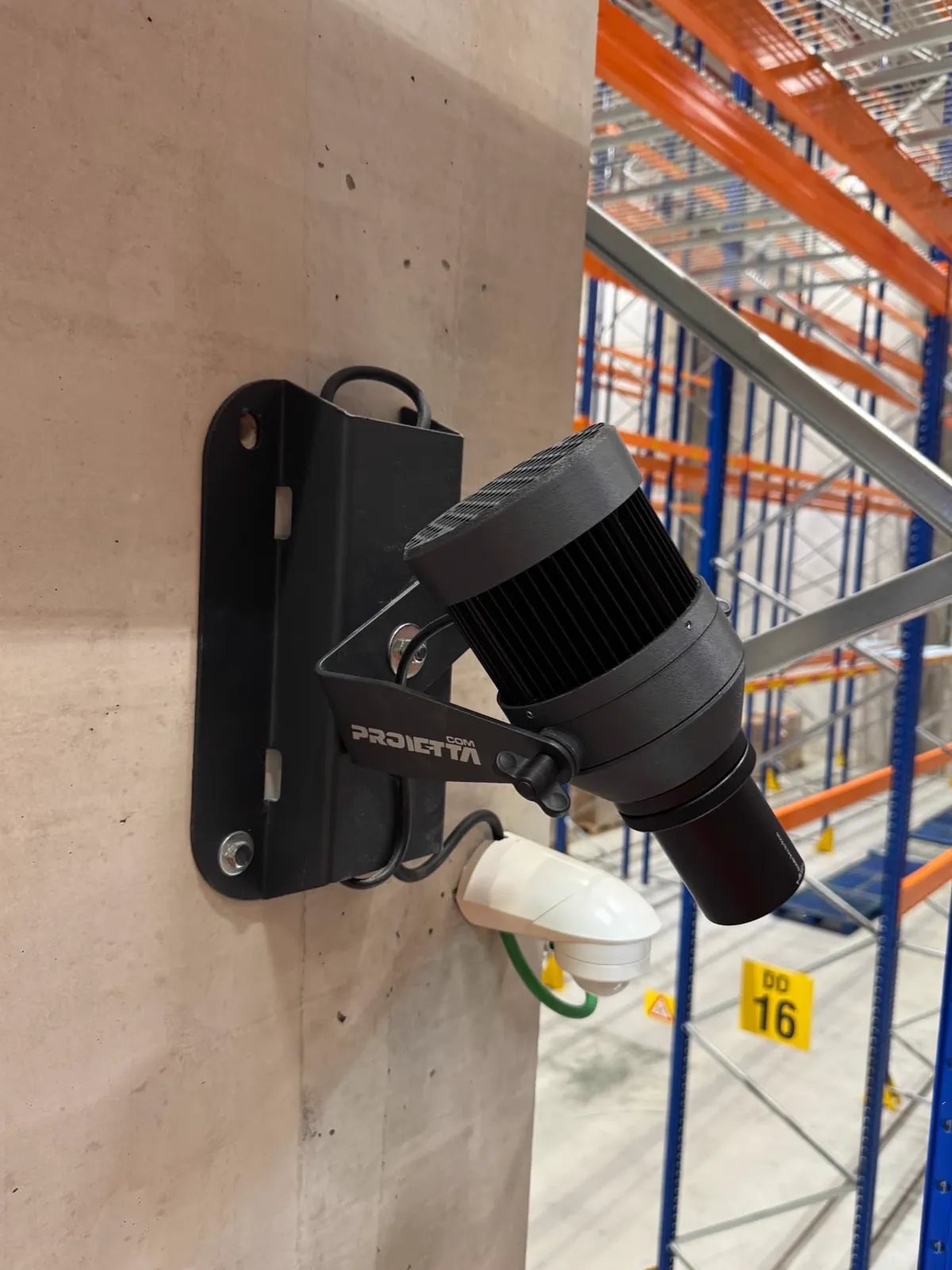 Gobo-projector van Proietta met bewegingsmelder, gemonteerd op een betonnen kolom in het magazijn