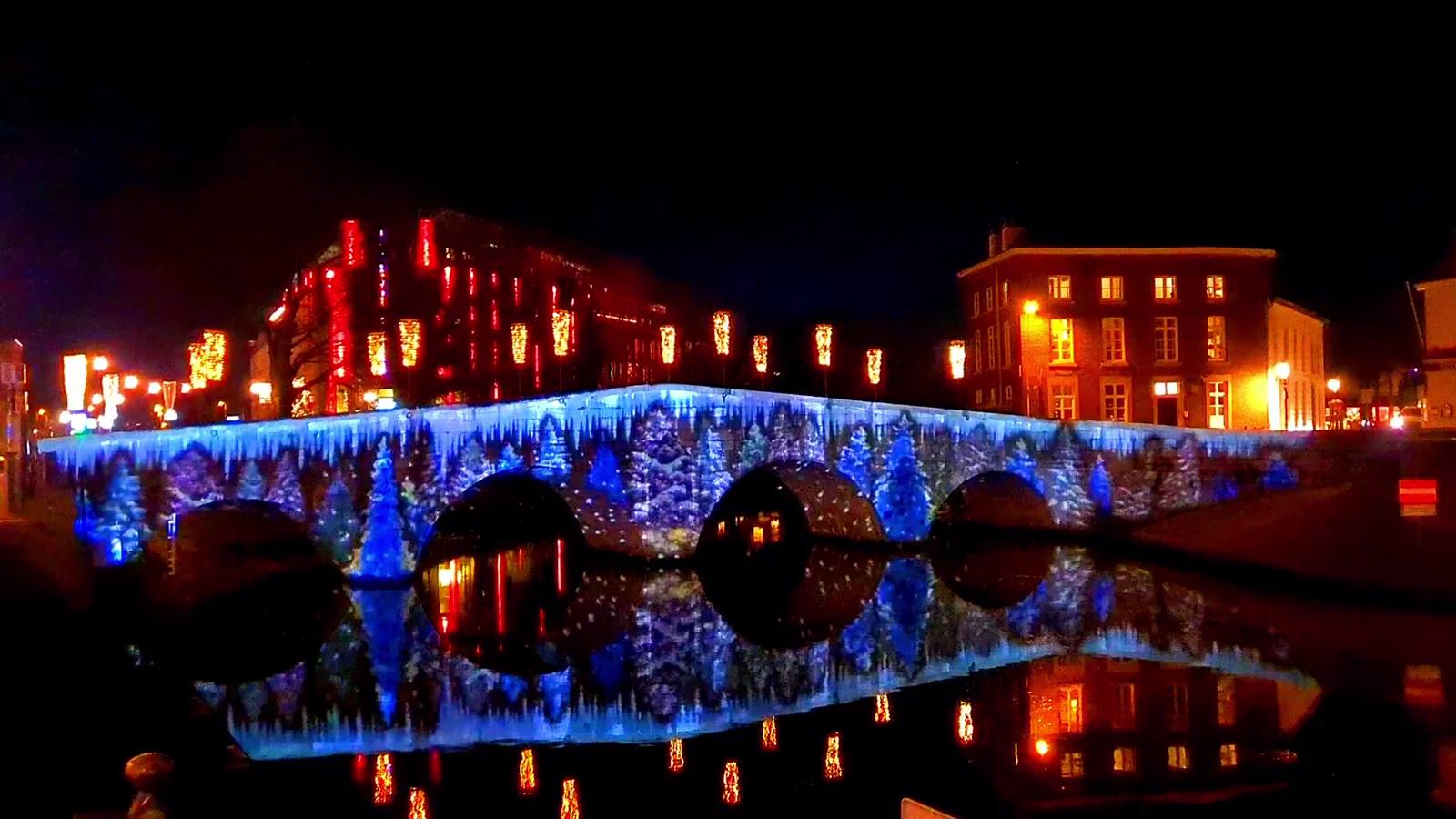 Brug in Roermond met blauwe lichtprojectie die weerspiegelt in het water tijdens ROERMONDVOL Licht
