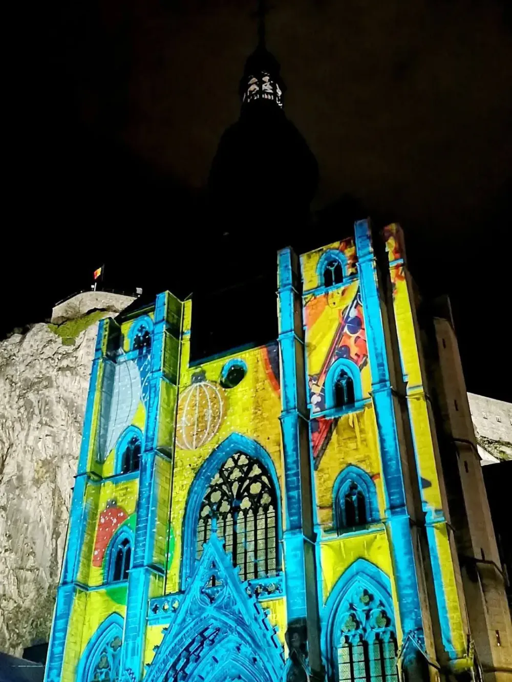 Kleurrijke gobo-projectie op de gevel van een gotische kerk bij nacht