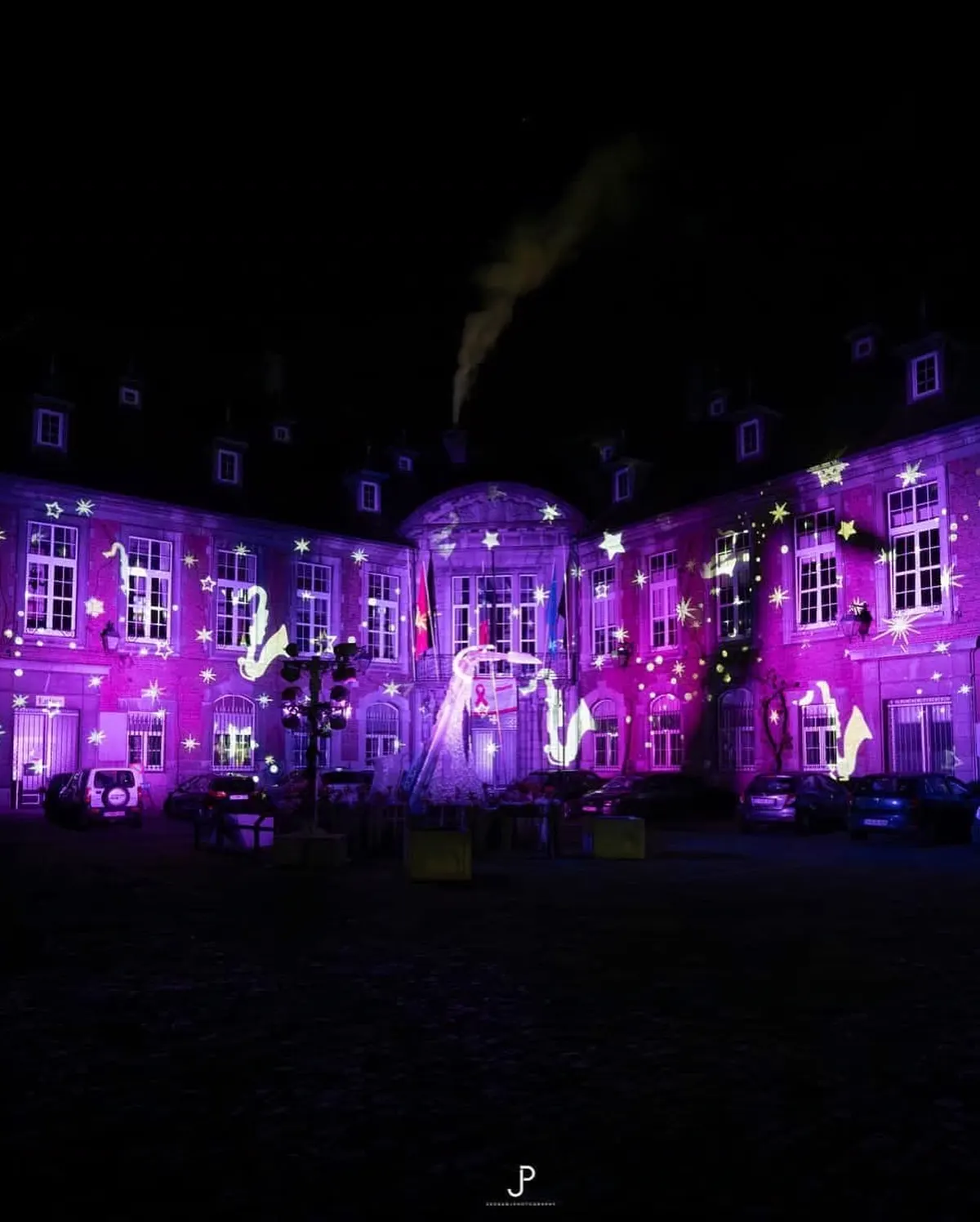 Paarse sterrenprojectie met saxofoonmotieven op een gevel in Dinant