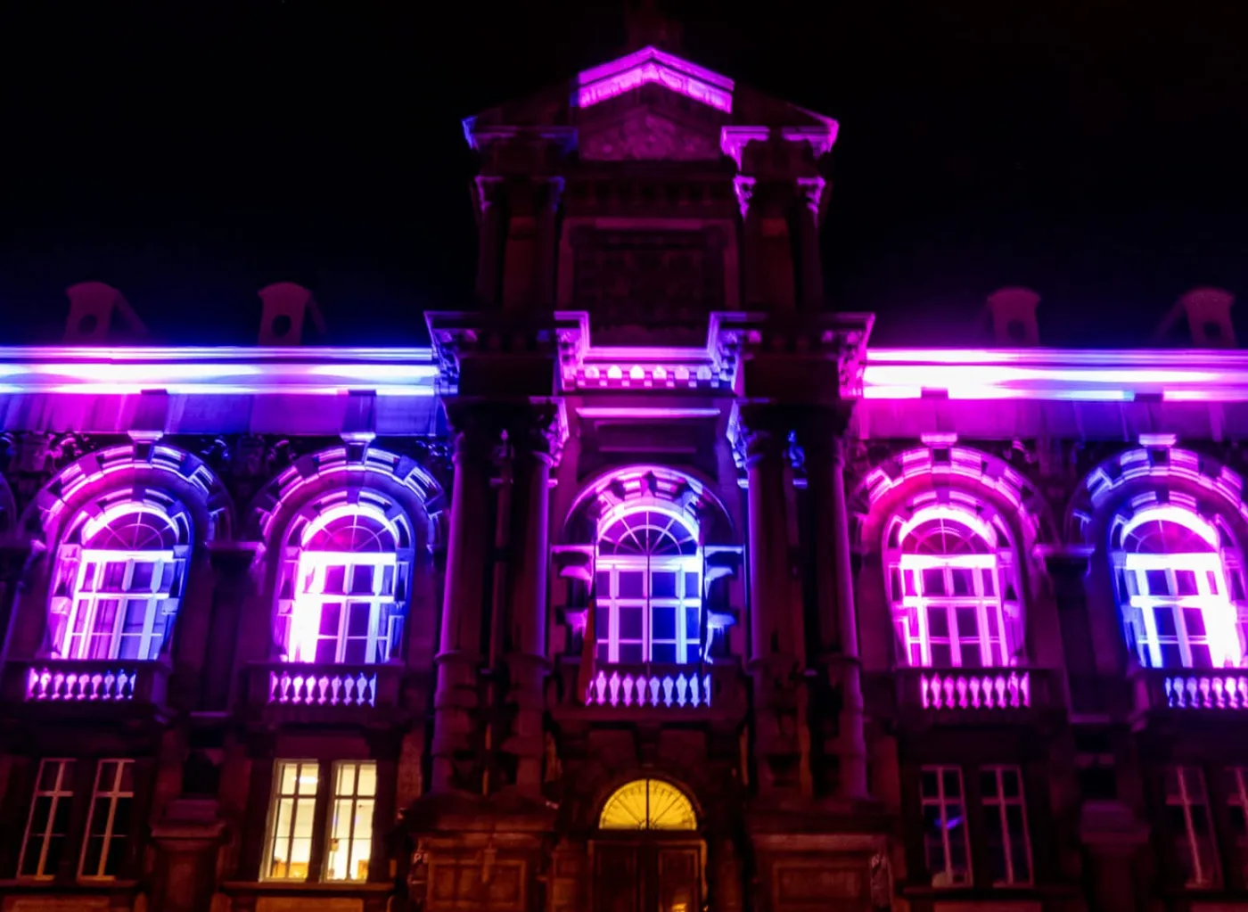 Historische gevel in paars en magenta licht bij nacht